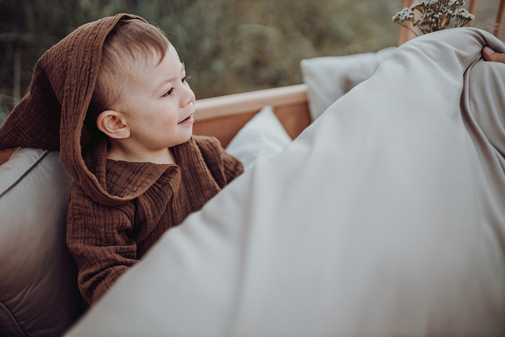 Dreng i barnseng omfavnet af økologisk sengetøj fra Favn København
